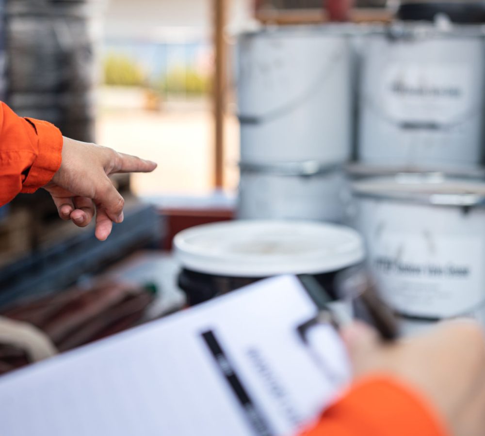 Činnost bezpečnostního pracovníka je ukázat na box s chemikáliemi v továrním skladu při provádění bezpečnostního auditu. Činnost bezpečnostního pracovníka je ukázat na box s chemikáliemi v továrním skladu při provádění bezpečnostního auditu.